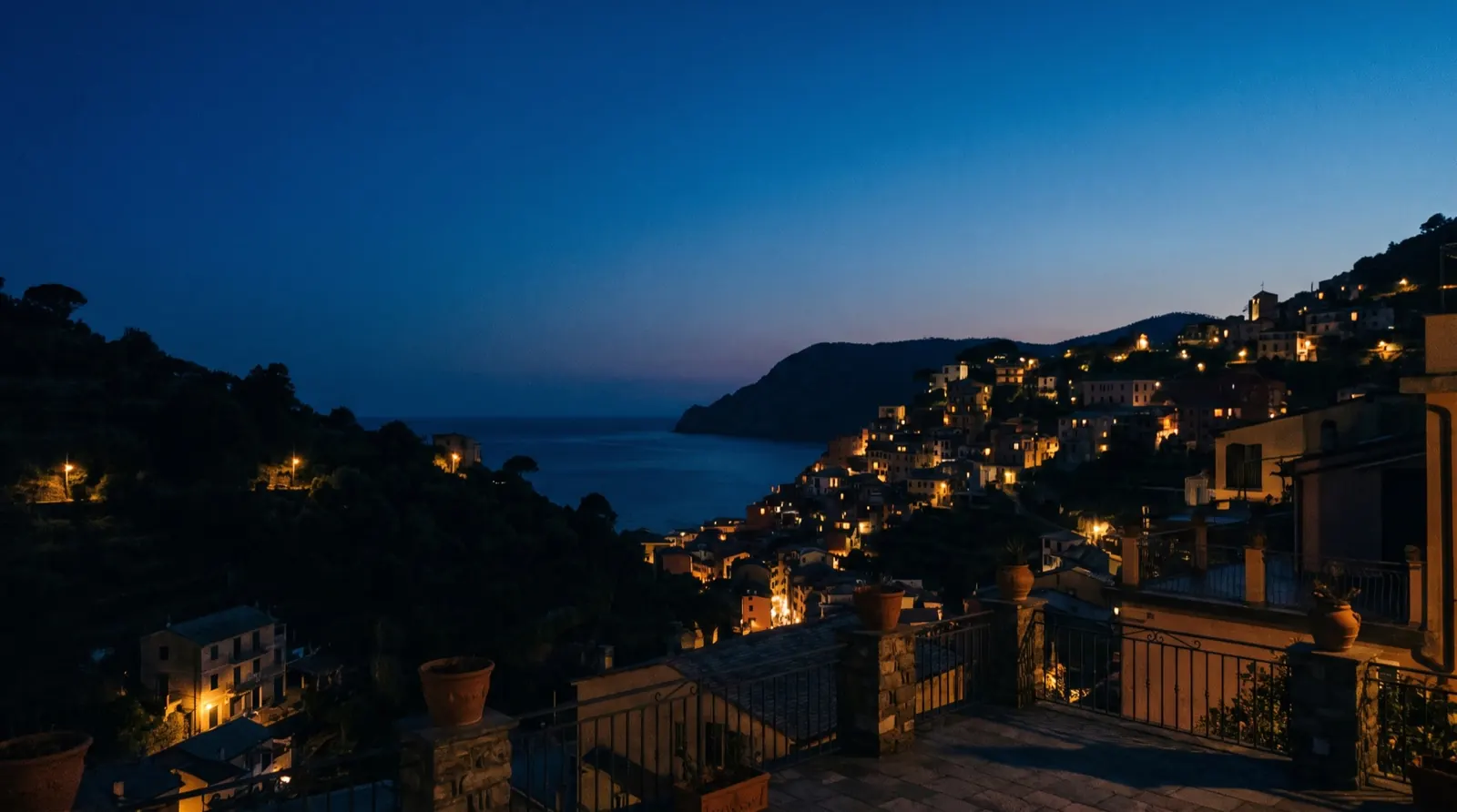Un paese sul mare al crepuscolo, con le luci delle case accese sulla costa